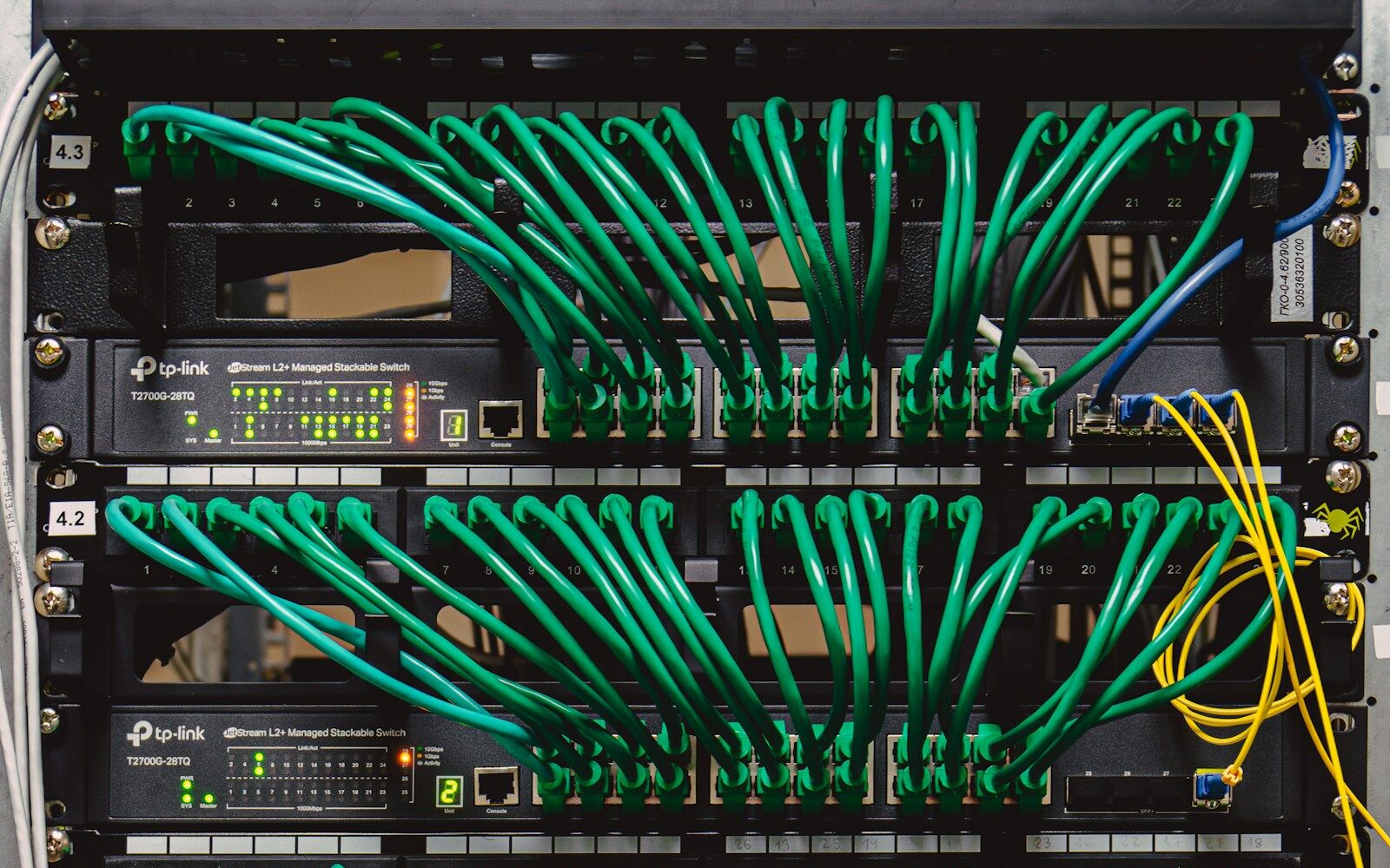 A network rack with color-coded patch cables dressed into switches